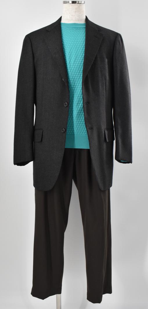 チャコールグレーのジャケットに、鮮やかなブルーグリーンのニットを合わせたスタイリング。