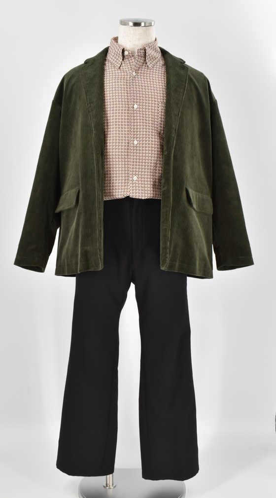 深いグリーンのジャケットに控えめな柄シャツと黒パンツを合わせた落ち着きのある大人の装い。